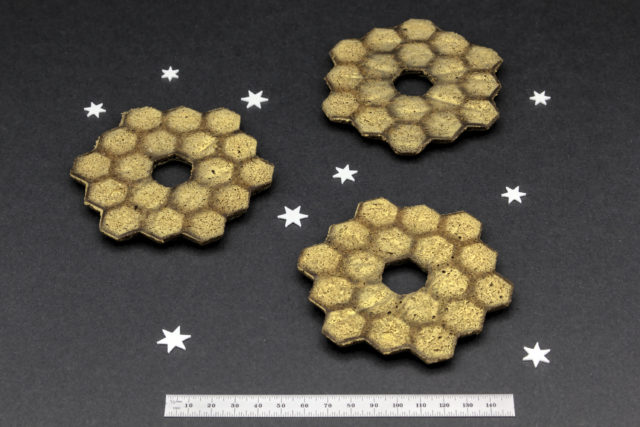Three gingerbread cookies in the shape of the JWST primary mirror with gold hexagonal segments stenciled on