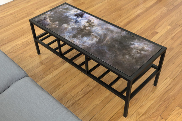 Black wooden coffee table with image of Tarantula Nebula on top and slats on the bottom