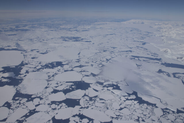 Sea ice and some snow-covered land view from the air.