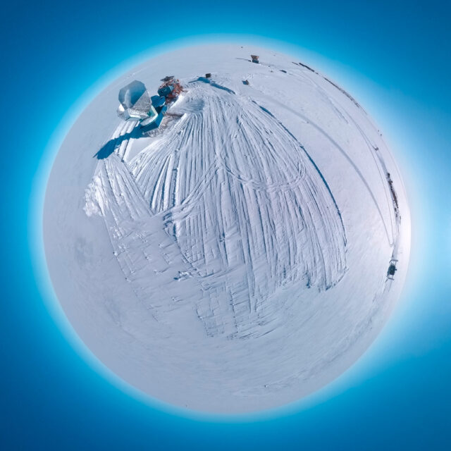 Aerial "little planet" view of a large, off-axis radio telescope on an ice sheet.